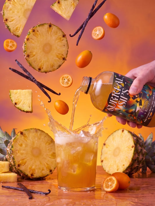 Surreal Sips Pineapple & Kumquat elixir poured over ice with fresh pineapple, oranges, and vanilla